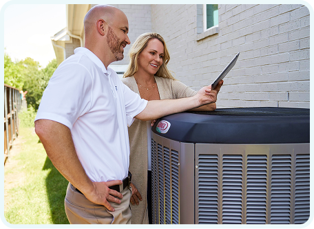 Technician showing a homeowner information on a tablet while standing beside an outdoor HVAC unit.